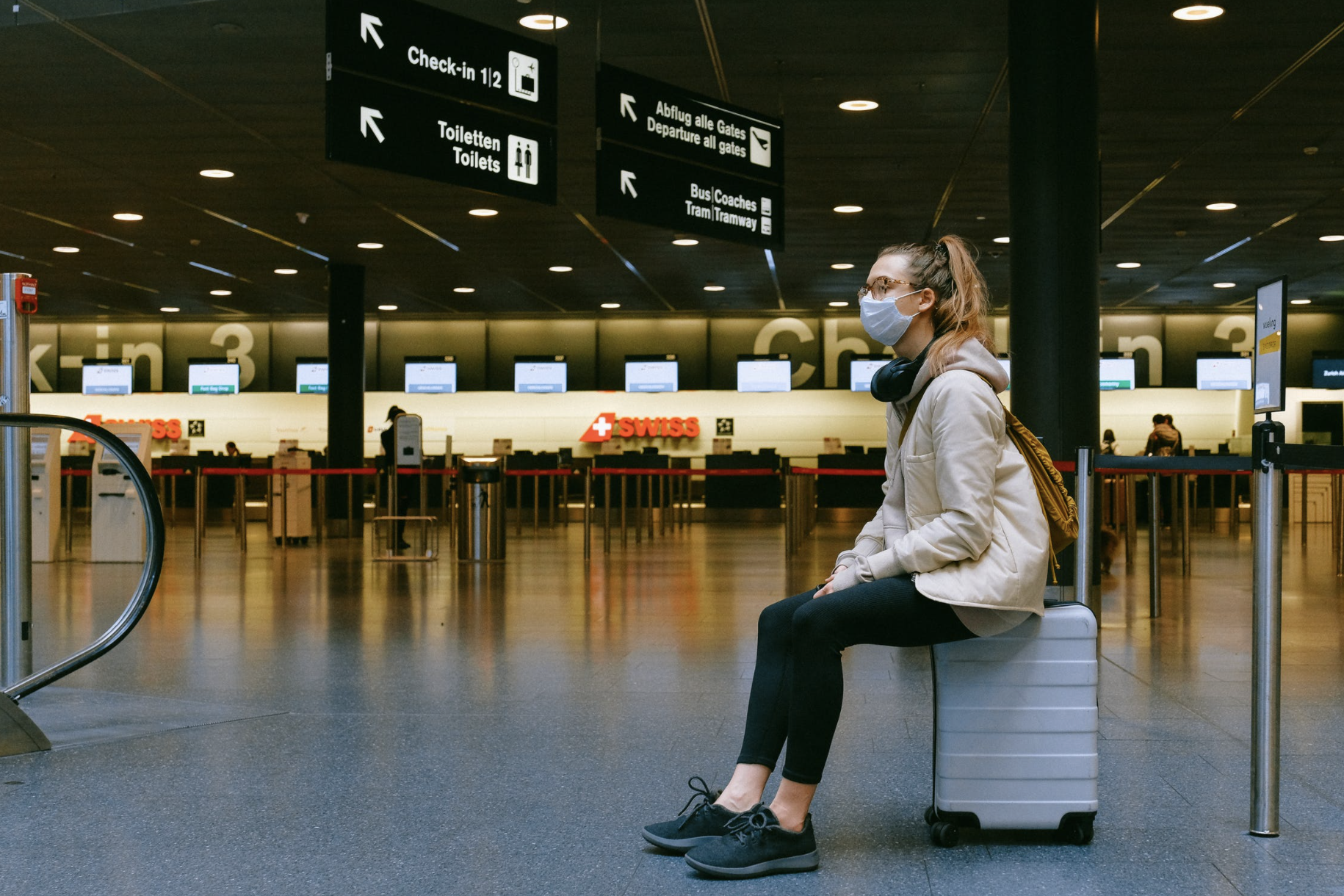 Woman sitting on luggage in airport, FAA